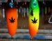 Two handmade lures in the workshop: a black one with an orange gradient and a green one with yellow, each with a black leaf pattern printed on it