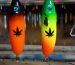 Two handmade lures in the workshop: a black one with an orange gradient and a green one with yellow, each with a black leaf pattern printed on it