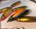 Workshop racks with hanging airbrushed lures in orange, green and blue-yellow colours